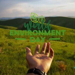 A hand extended towards a lush green landscape with rolling hills under a clear sky. The text "World Environment Day" is overlaid in green with leaf illustrations, symbolizing environmental awareness and action.