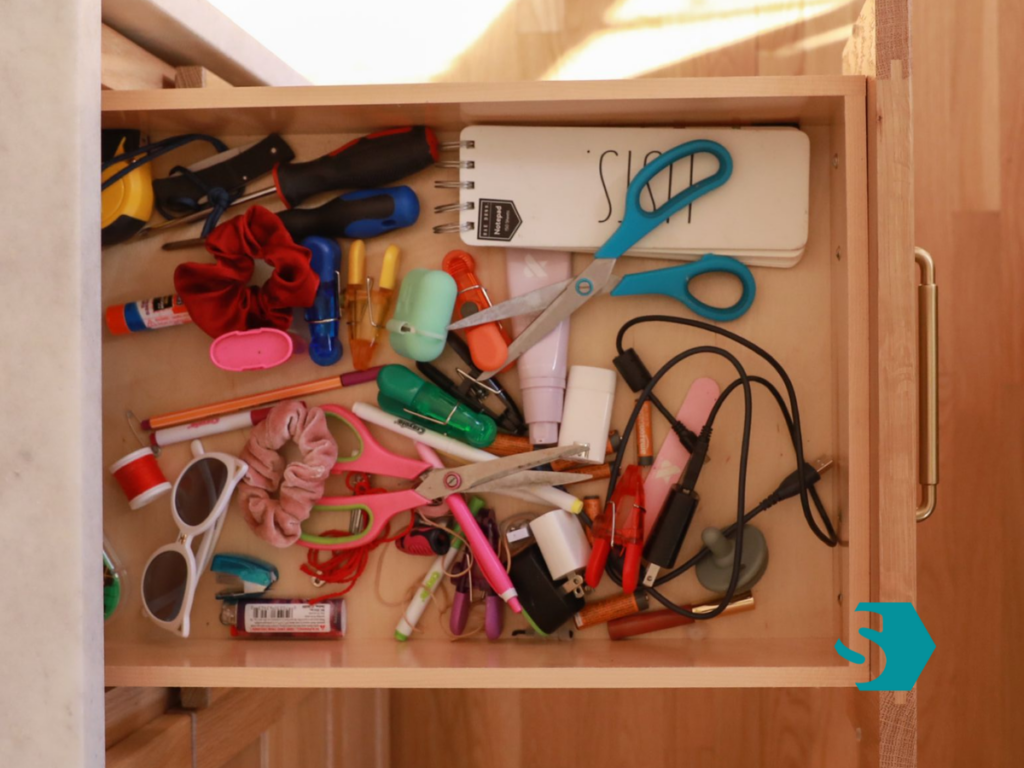 Messy junk drawer filled with random household items before organizing